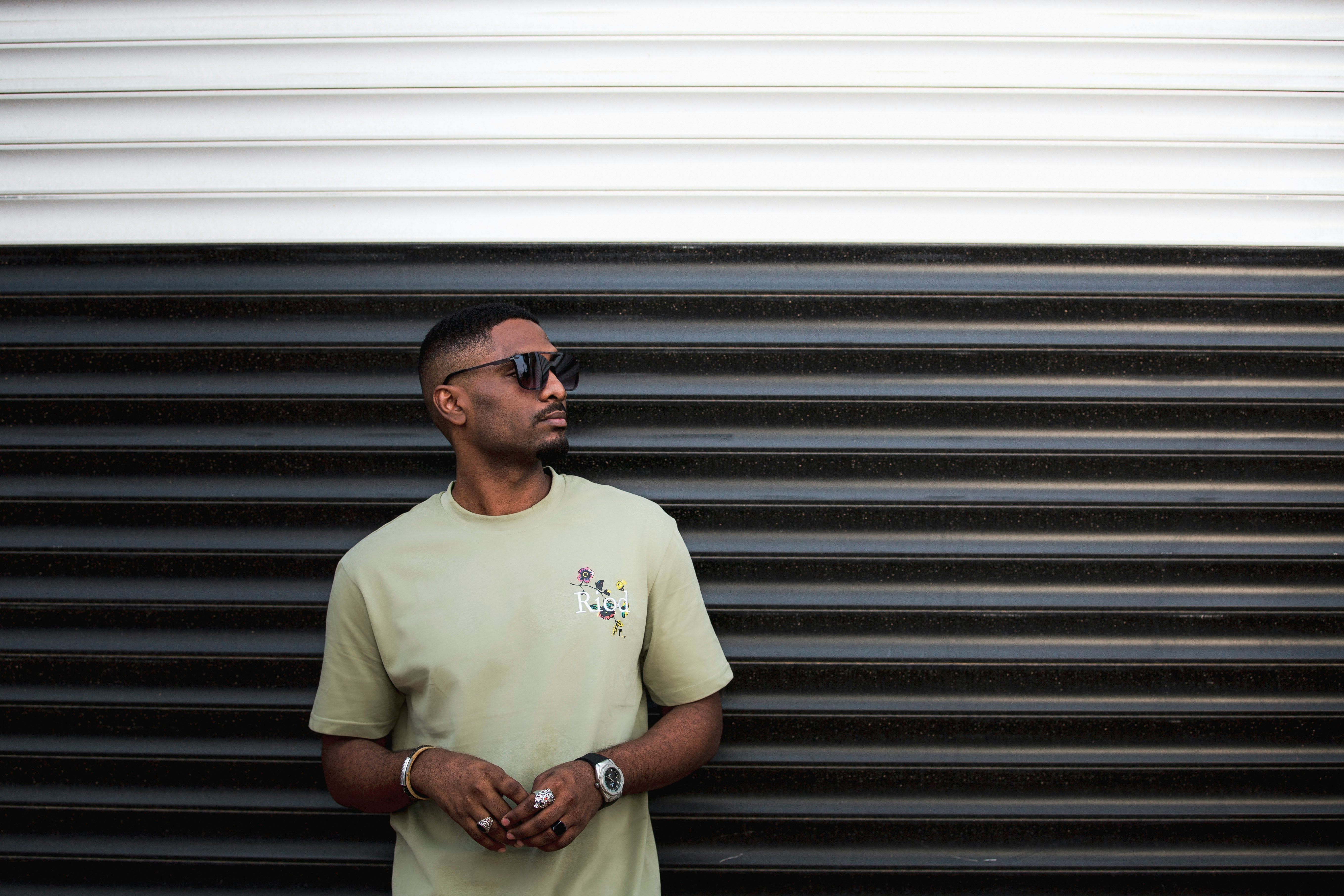 man in white crew neck t-shirt standing beside roll up door